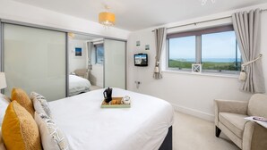 Una camera d'albergo moderna con un letto grande, un divano, una TV e una finestra con vista.