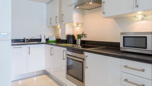 A modern kitchen with stainless steel appliances, white cabinetry, and under-cabinet lighting. - 28 Rocklands, a stylish and contemporary Cornish escape (Newquay)