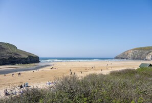 Una spiaggia con persone, una tenda e una scogliera.
