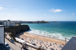 A coastal beach with a rocky cliff, a sandy shore, and a view of the sea. - Sandcastles offers a delightful two-bedroom self-catering apartment (Mawgan Porth)
