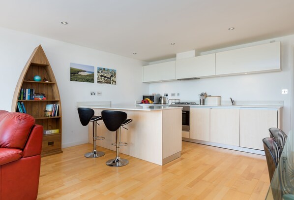 A modern kitchen with white cabinets, a central island, and two bar stools.