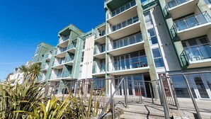 Un edificio de varios pisos con balcones, una escalera y cielo despejado.