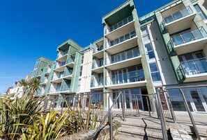 A multi-story building with balconies, a staircase, and a clear sky.