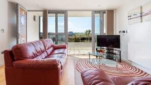 Una sala moderna con un sofá de cuero, una mesa de centro de cristal y un televisor de pantalla plana.