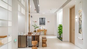 En moderne hotellobby med en receptionsdisk, træbøtter, en plante og kunst på væggene.