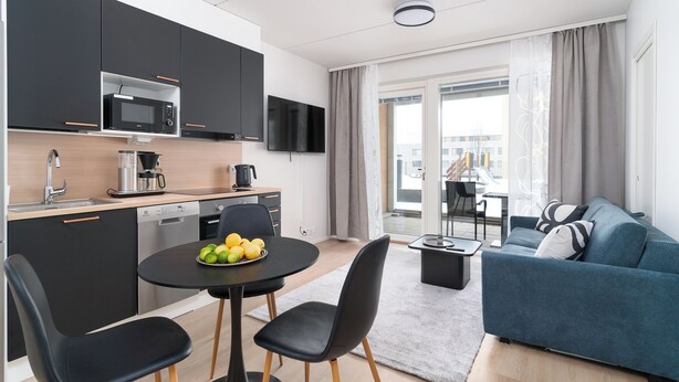 Eine moderne Wohnung mit Küche, Essbereich und Wohnzimmer. Sie verfügt über eine Mikrowelle, eine Kaffeemaschine und einen Flachbildfernseher.