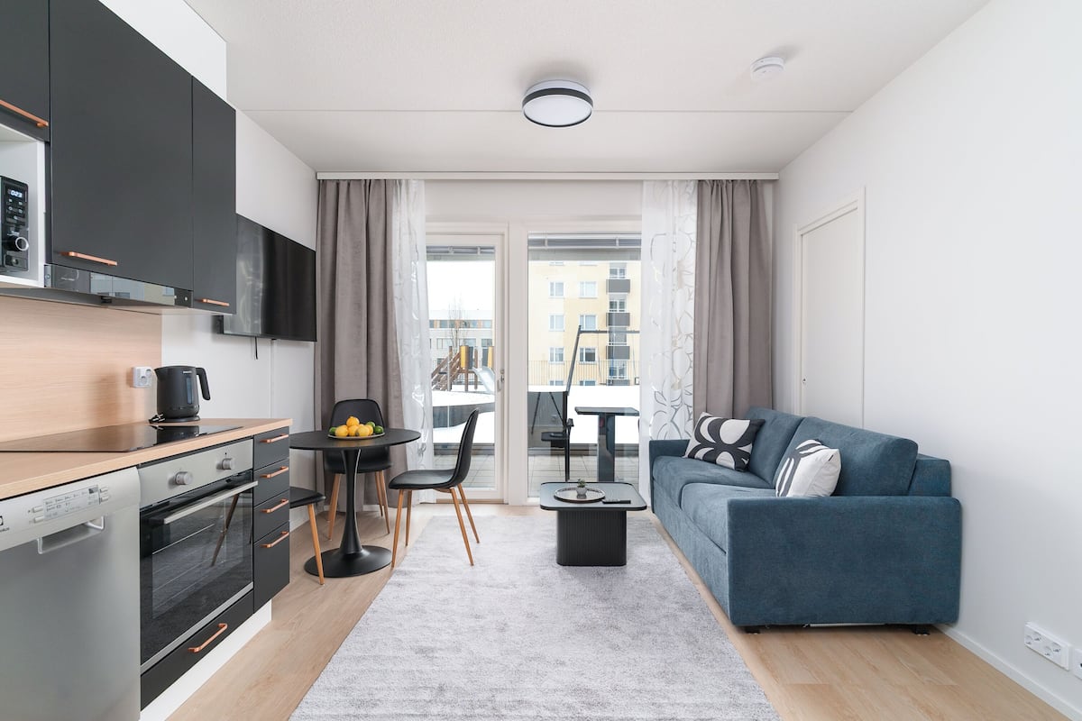 Un apartamento moderno con cocina, comedor y sala de estar. Incluye un sofá, una mesa de centro y una mesa de comedor con sillas.