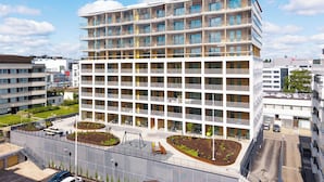 Ein mehrstöckiges Hotel mit Balkonen, einem Parkplatz und einem begrünten Innenhof.