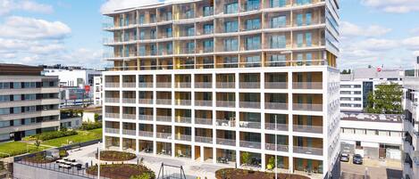 Un hotel de diverses plantes amb balcons, una zona d'aparcament i un pati paisatjístic.
