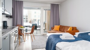 Ein modernes Hotelzimmer mit Küchenzeile, Essbereich, einer Couch und einem Bett.
