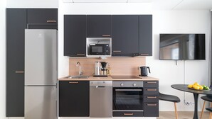 Eine moderne Küche mit Kühlschrank, Mikrowelle, Geschirrspüler, Ofen sowie ein Essbereich mit Tisch und Stühlen.