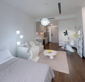 A modern, minimalist bedroom with a large bed, a bedside table, and a small round table with a bowl of lemons.