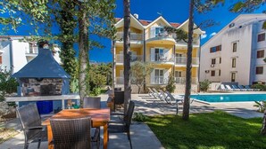 Un espace aménagé au bord de la piscine, comprenant une table et des chaises, un barbecue et une piscine.