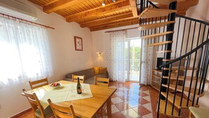 Un espace repas comprenant une table et des chaises en bois, un canapé et un escalier avec une rampe en bois.