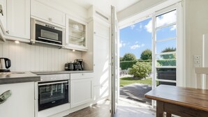 A modern kitchen with white cabinetry, a built-in oven, and a coffee maker. - Spacious 3-room apartment on approx. 80 m² for up to 4 people in Westerland (Westerland)
