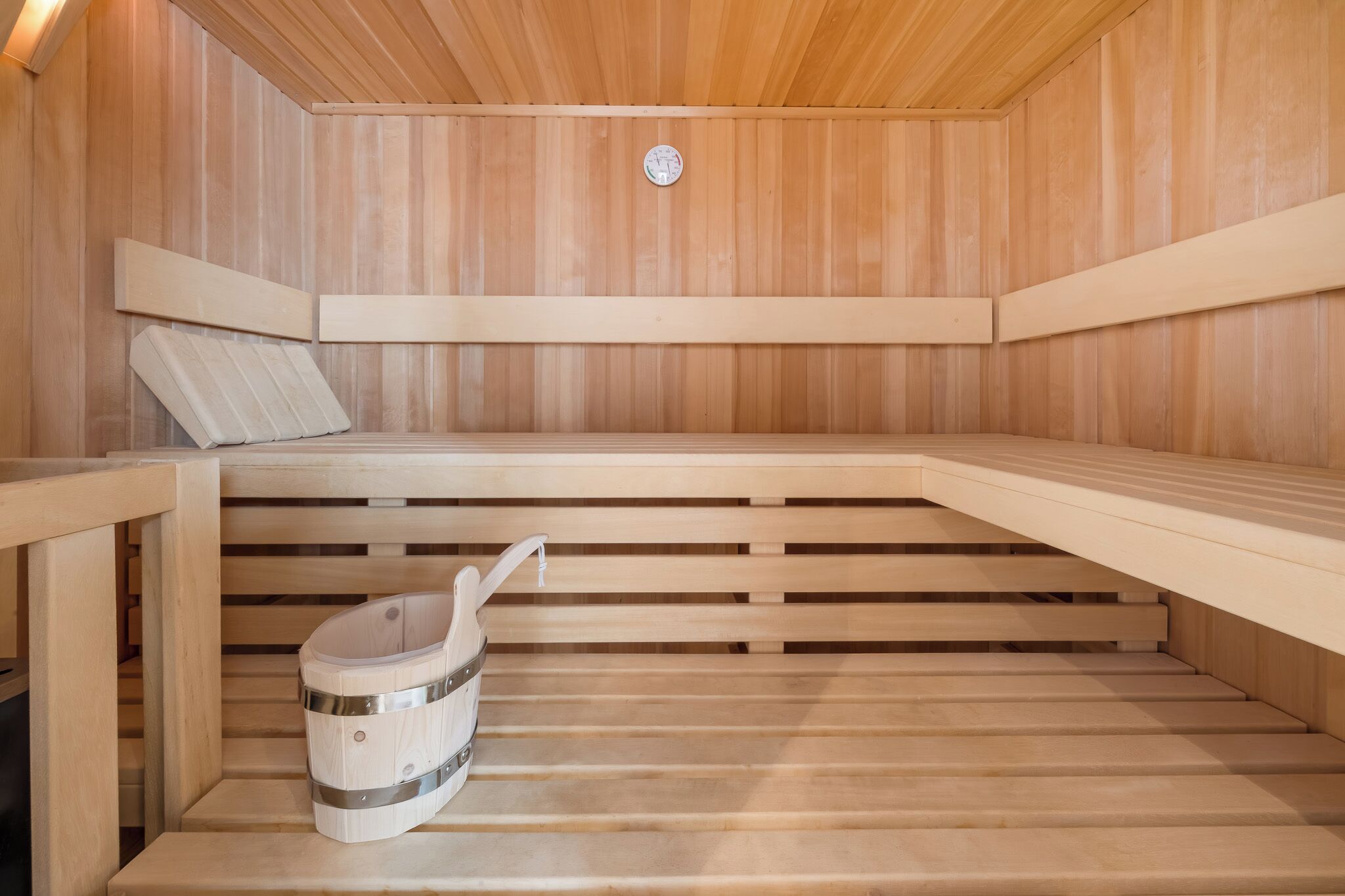 Una sauna con bancos de madera y un cubo de madera.