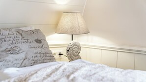 Ein ordentlich bezogenes Bett mit einem Zierkissen und einer Lampe mit einer strukturierten Lampenschirm.