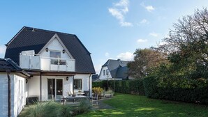 A house with a sloped roof, a balcony, and a well-maintained lawn. - Bright 3-room apartment with approx. 70 m² for up to 4 people (Westerland)