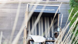A sunroom with striped curtains and a bench. - Bright 3-room apartment with approx. 70 m² for up to 4 people (Westerland)