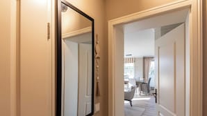 A hallway with a large mirror, a door leading to a dining area, and a light-colored carpet. - Bright 3-room apartment with approx. 70 m² for up to 4 people (Westerland)