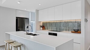 Eine moderne Küche mit Kochinsel, Edelstahlgeräten und einer strukturierten Spritzschutzwand.