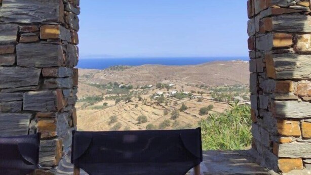 A stone-walled room with a view of a hilly landscape and the sea. - Kea's Hidden Diamond (Otzias)