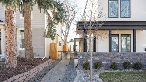 A modern residential building with a stone facade, large windows, and a well-maintained lawn. - Trendy Tennyson Flat (Denver)