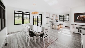 Una cocina moderna con armarios blancos, una isla grande y un comedor con mesa y sillas.