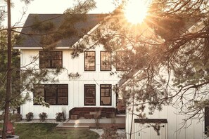 A two-story house with a front porch, large windows, and a visible garage.