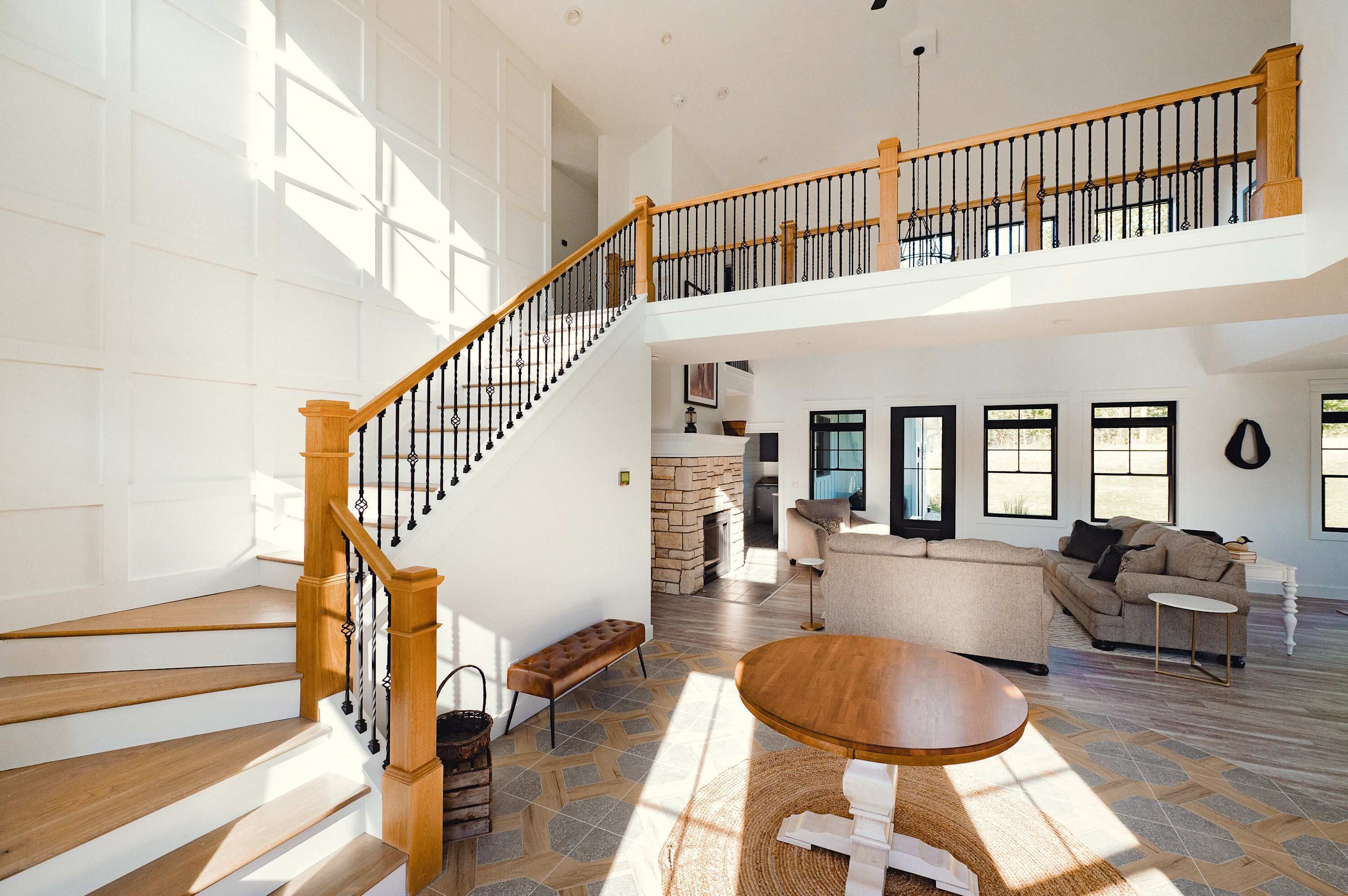 A spacious living area with a wooden staircase, a stone fireplace, and a large sofa.
