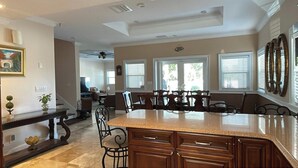 Una cocina amplia con una isla grande, armarios de madera oscura y una zona de comedor con sillas.