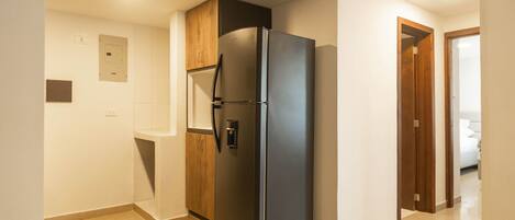 A kitchen with a black refrigerator, wooden cabinets, and a tiled floor.