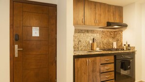 A kitchen with wooden cabinets, a granite countertop, a stove, and an oven. - w* | Delightful 2BR in Bocagrande (Cartagena de Indias)