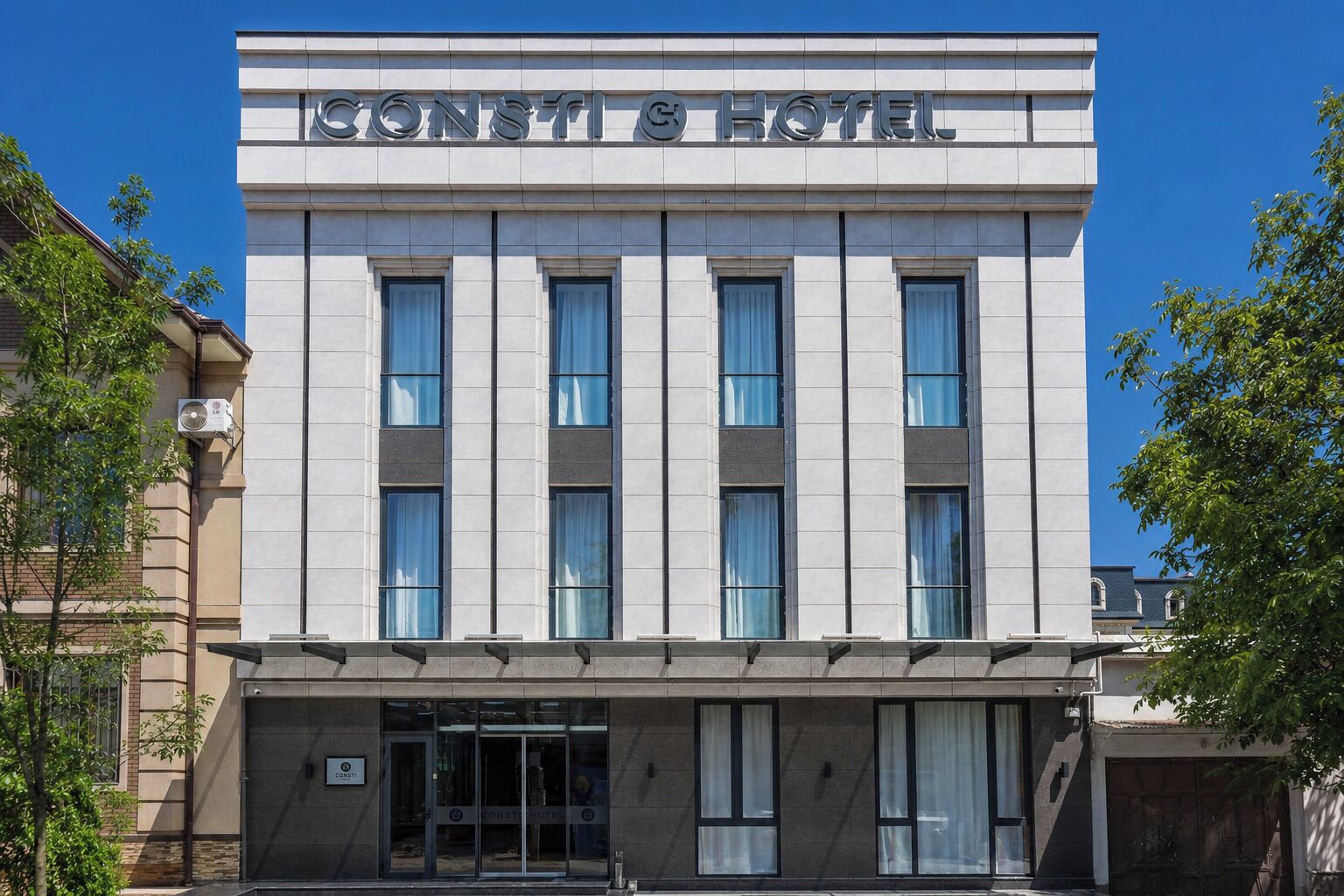 Un hotel con fachada moderna, amplias ventanas y cielo despejado.
