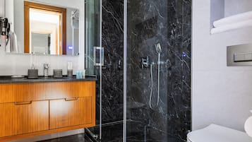 Une salle de bain moderne avec une douche à parois de verre, un meuble-lavabo en bois et des toilettes blanches.