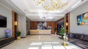 Un hall d'hotel modern amb una recepció, un sofà i una gran pèndol.