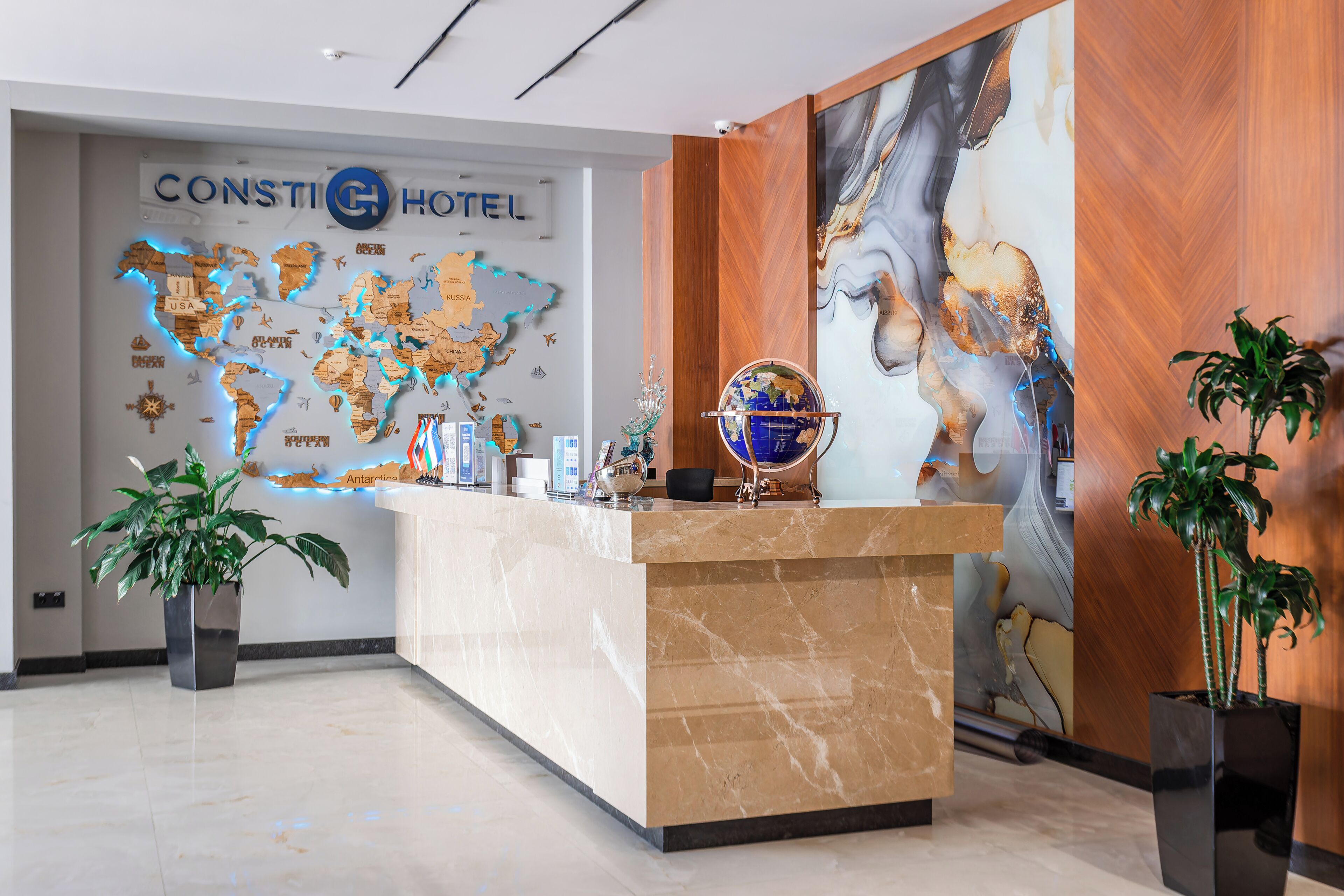 Een hotel receptie met een wereldkaart, een aardglobe en een wandpaneel van hout.