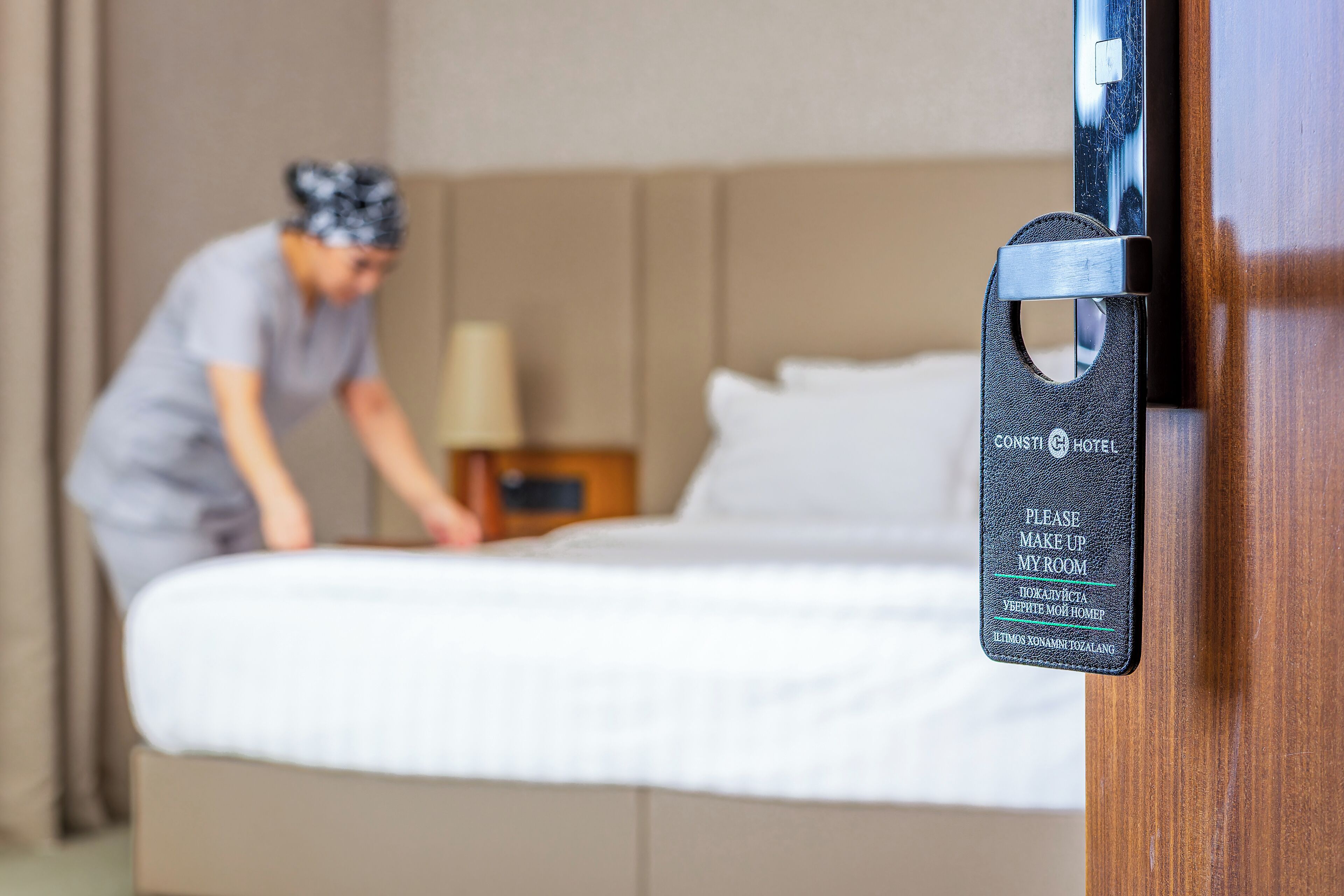 Et hotelværelse med en seng, et natbord og et panel monteret på væggen.