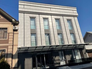 A modern building with a flat roof, large windows, and a covered entrance area. - Consti Hotel Tashkent (Tashkent)
