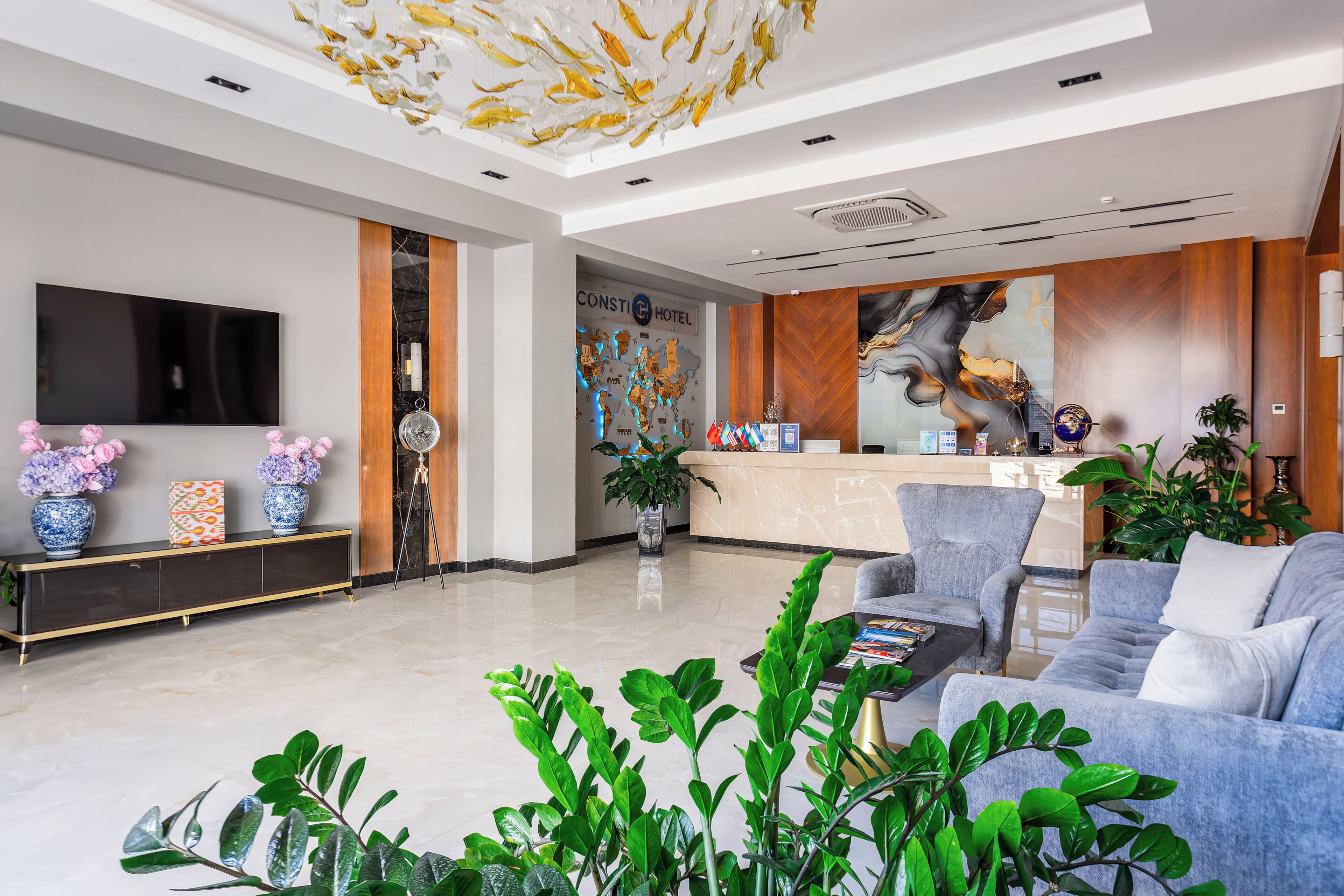 A hotel lobby with a reception desk, seating area, and a large flat-screen TV.