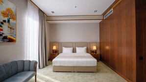 Habitació d'hotel moderna amb un llit gran, un sofà i un quadre a la paret.