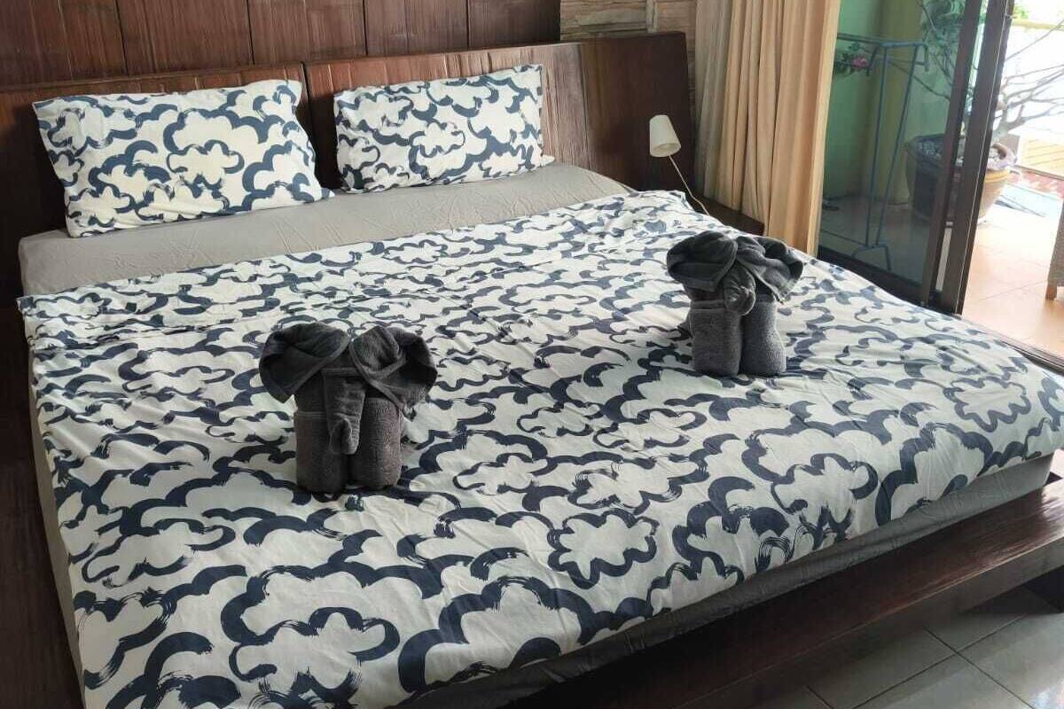 Una cama con una colcha estampada, dos almohadas y dos toallas sobre la misma.