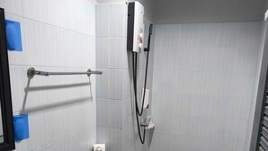 A bathroom with a sink, toilet, towel rack, and a shower unit. - Kata Happy Place (Karon)