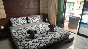 A bed with a patterned bedspread, two pillows, and a pair of slippers on it. - Kata Happy Place (Karon)