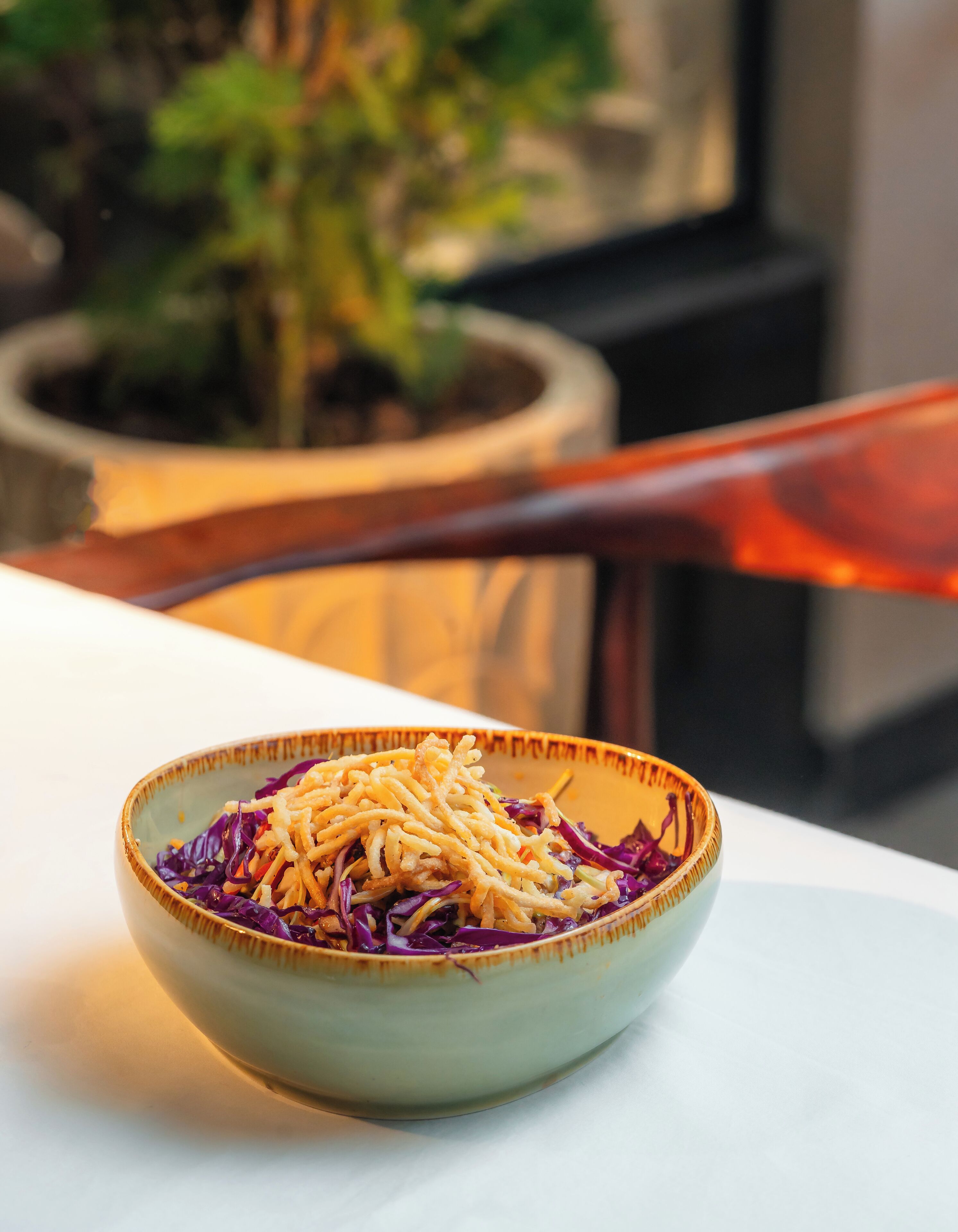 A bowl of noodles with purple cabbage on a table.