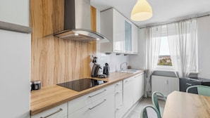 A modern kitchen with wooden cabinetry, a built-in stove, and a window with curtains. - City Apartment | View & WIFI (Kempten (Allgäu))