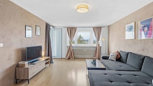 A modern living room with a flat-screen TV, a grey sofa, and a wooden entertainment unit. - City Apartment | View & WIFI (Kempten (Allgäu))