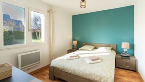 A bedroom with a bed, bedside tables, a window, and a view of the outdoors. - Comfortable T3, walking distance to the beach - Secure garage (Dinard)