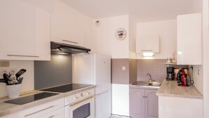 A modern kitchen with white cabinetry, a black countertop, and a built-in oven. - Comfortable T3, walking distance to the beach - Secure garage (Dinard)