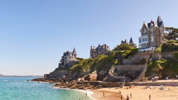 A coastal scene with a large, historic building on a cliff overlooking a beach. - Comfortable T3, walking distance to the beach - Secure garage (Dinard)